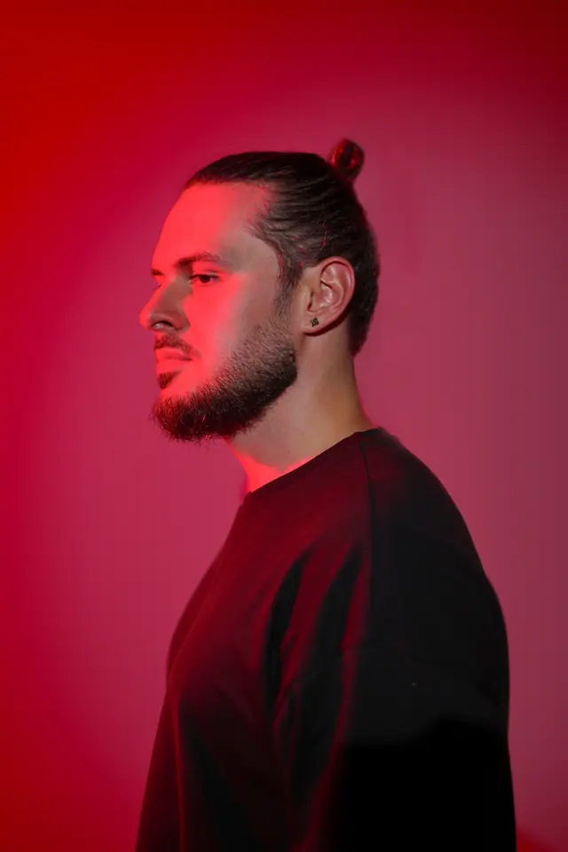 Studio profile portrait of OPPAACHA against a red backdrop